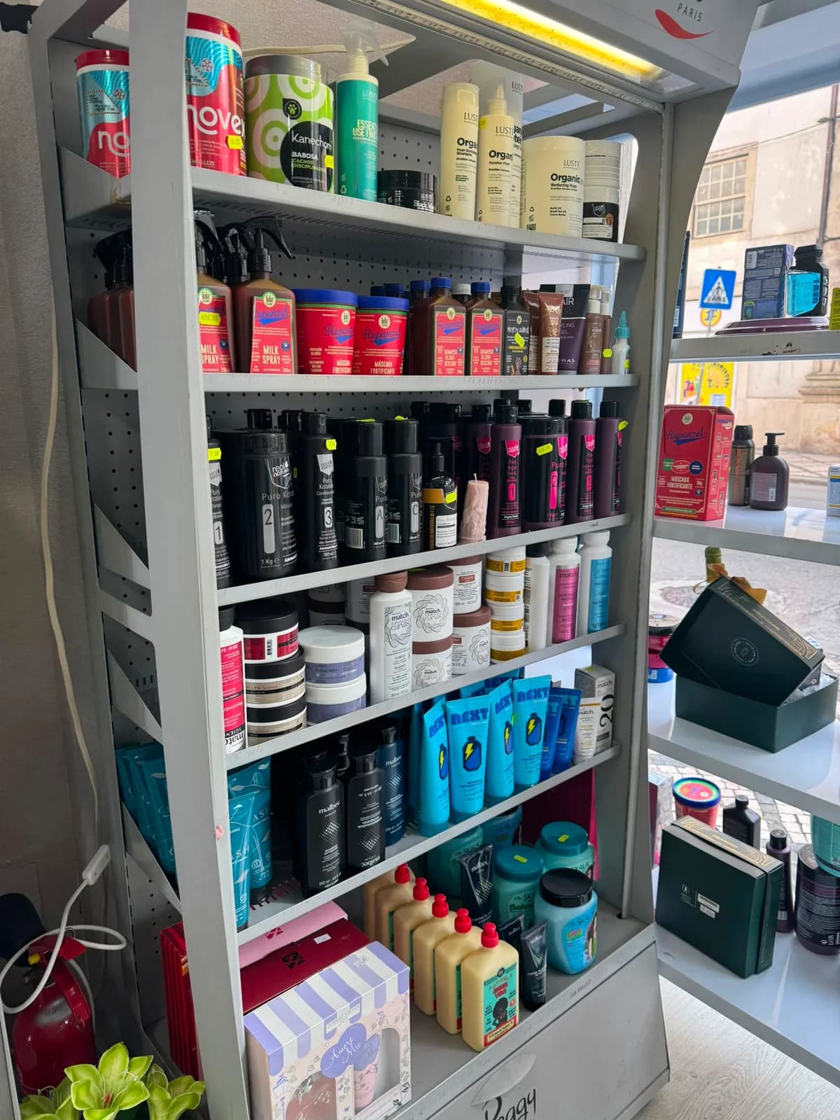 Prateleiras de cosmética e cuidado do cabelo, com a rua visível pela montra